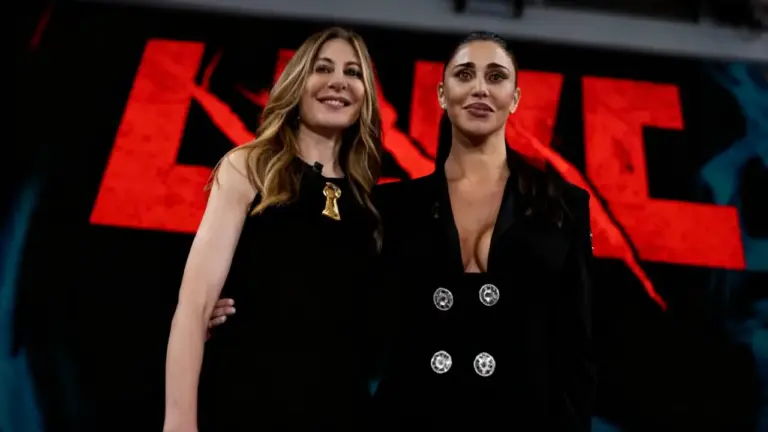 Due donne in abiti eleganti posano sul set di un programma televisivo