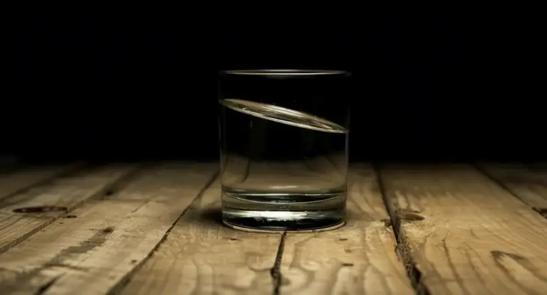 Bicchiere d'acqua su tavolo di legno con sfondo scuro