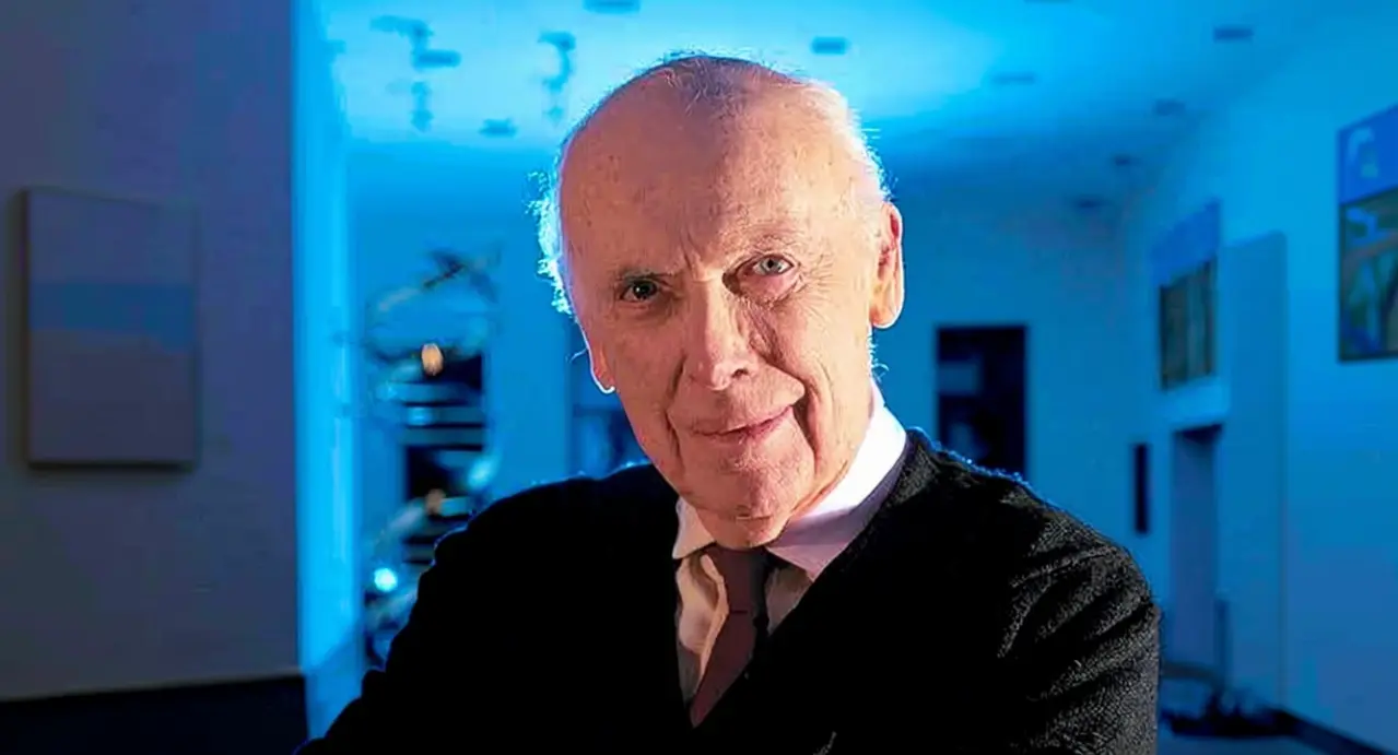 Un uomo anziano in primo piano in un ambiente scientifico illuminato di blu