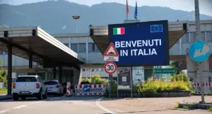 Auto al valico di frontiera tra Svizzera e Italia con cartello di benvenuto