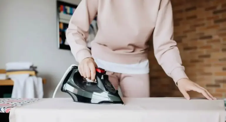 Persona che stira una camicia su un'asse da stiro in ambiente domestico