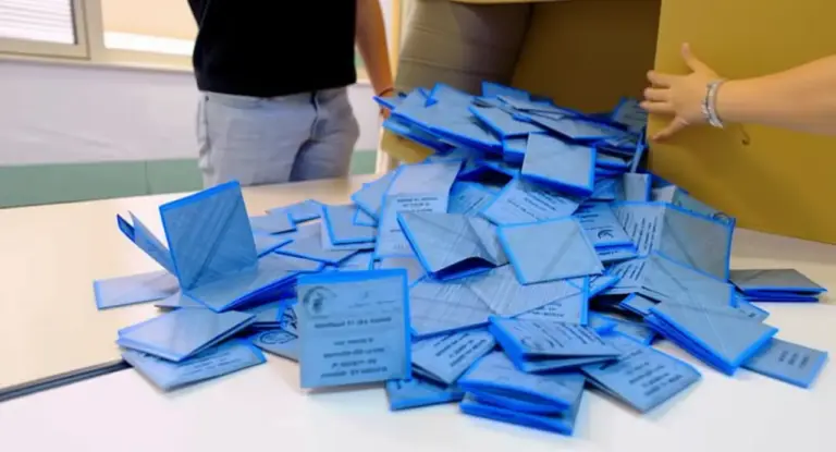 Schede elettorali blu su un tavolo durante lo spoglio dei voti.