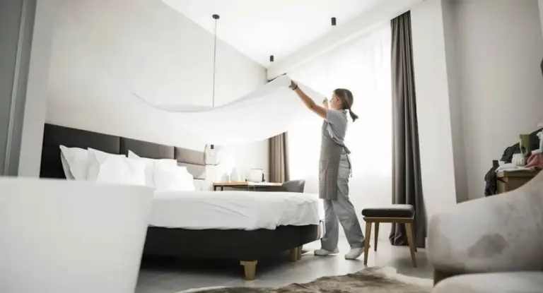 Una persona sistema le lenzuola in una stanza luminosa di un B&B