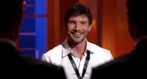 Una persona sorridente in primo piano sul set di un programma televisivo