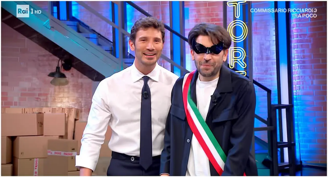Due persone in uno studio televisivo, una indossa una fascia tricolore italiana