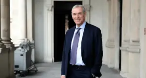 Un uomo in abito formale in un portico con colonne, sorridente alla fotocamera