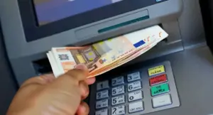 Persona preleva banconote da uno sportello bancomat