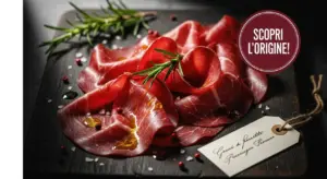 Fettine di bresaola su tagliere con rosmarino, pepe rosa e sale grosso