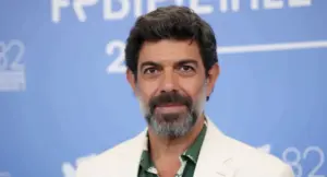 Un uomo con barba e capelli brizzolati su sfondo blu, in posa per una foto ufficiale