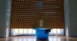 Secchio blu con panno davanti a tapparella parzialmente abbassata