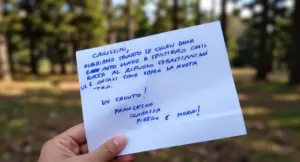 Una mano tiene un biglietto scritto a mano all'aperto in un parco o bosco